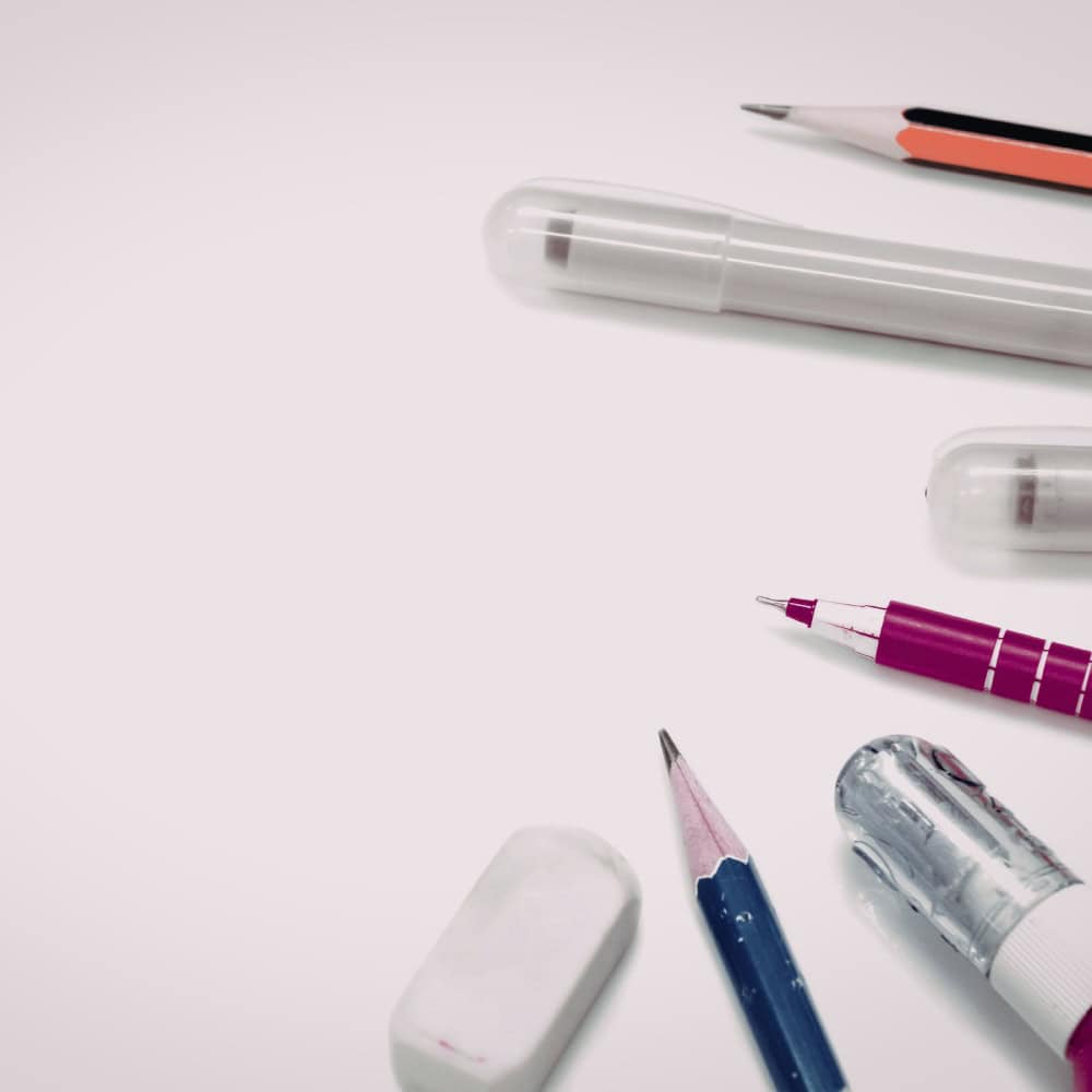 Assorted stationery items including pens, a mechanical pencil, an eraser, and a highlighter on a white background.